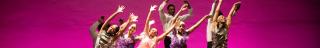 dancers on stage leap with arms raised